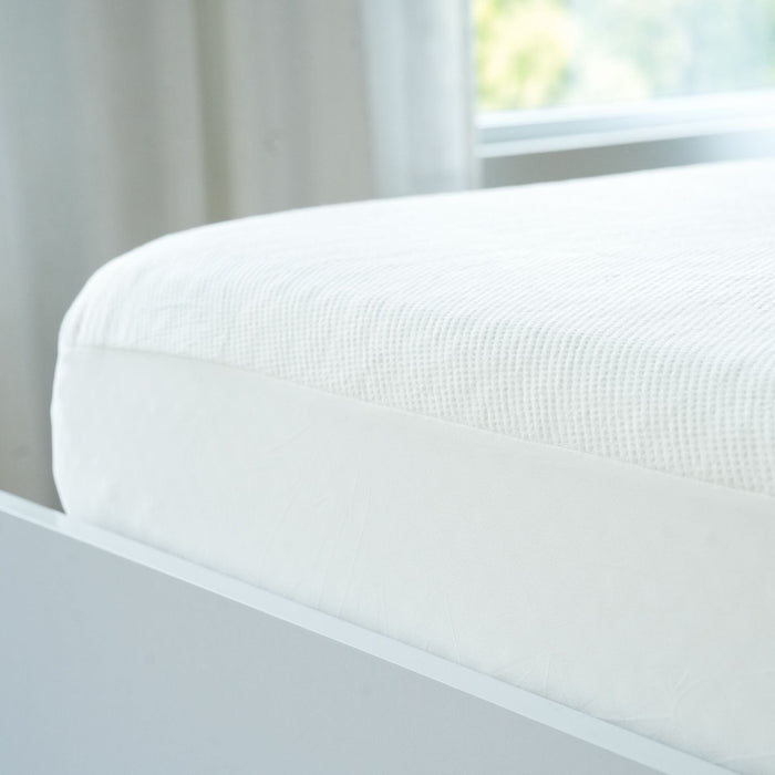 White mattress on modern bed frame in bright bedroom.