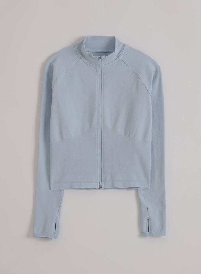 Vaaleansininen aim'n Aura Shape Seamless Zip Jacket peukalorei'illä ja täyspitkällä vetoketjulla tasokuvassa.