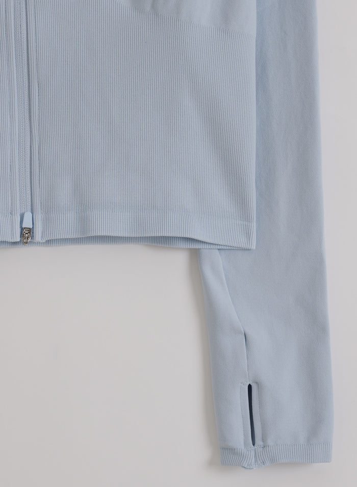 Vaaleansininen Aura Shape Seamless Zip Jacket, jossa on resorihelma ja peukaloreiällinen hiha.