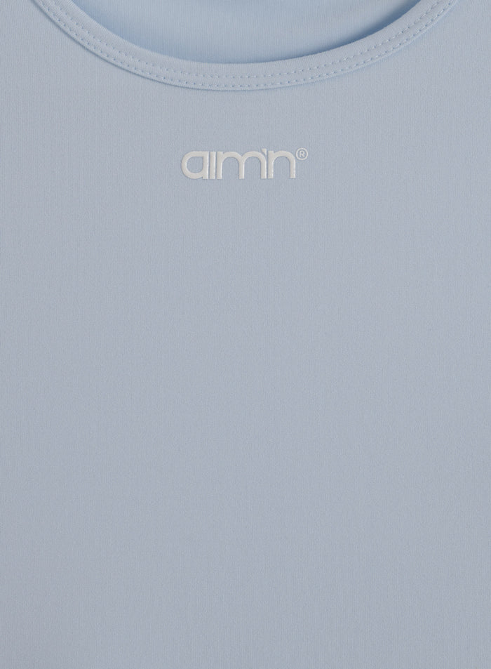 Vaaleansininen Soft Basic Singlet, jossa on pyöreä pääntie ja valkoinen painettu aim'n-logo.