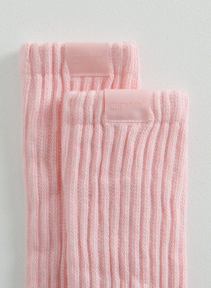Lähikuva vaaleanpunaisista ribatuista Slouch Socks -sukista, joissa on huomaamaton aim'n-logomerkki