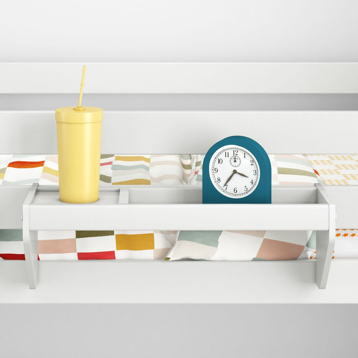 Bunk bed shelf organizer with yellow travel cup and teal alarm clock on colorful patterned children's bedding