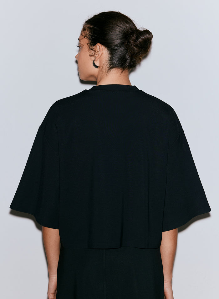 Nainen takaapäin yllään musta Luxe Boxy Short Sleeve -toppi. [M-170CM]