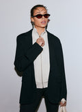 Nainen yllään musta Luxe Relaxed Blazer, vaalea vetoketjullinen toppi ja aurinkolasit [40-170CM]