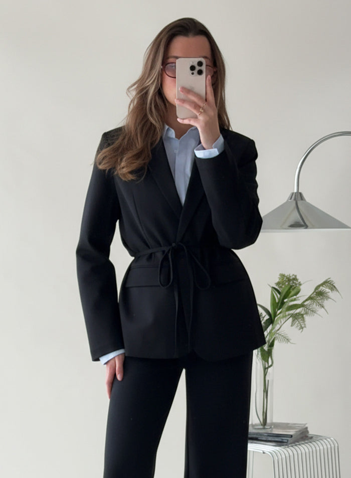 Peiliselfie naisesta, jolla on yllään musta Luxe Relaxed Blazer vyötärönauhalla stailattuna [38-175cm]