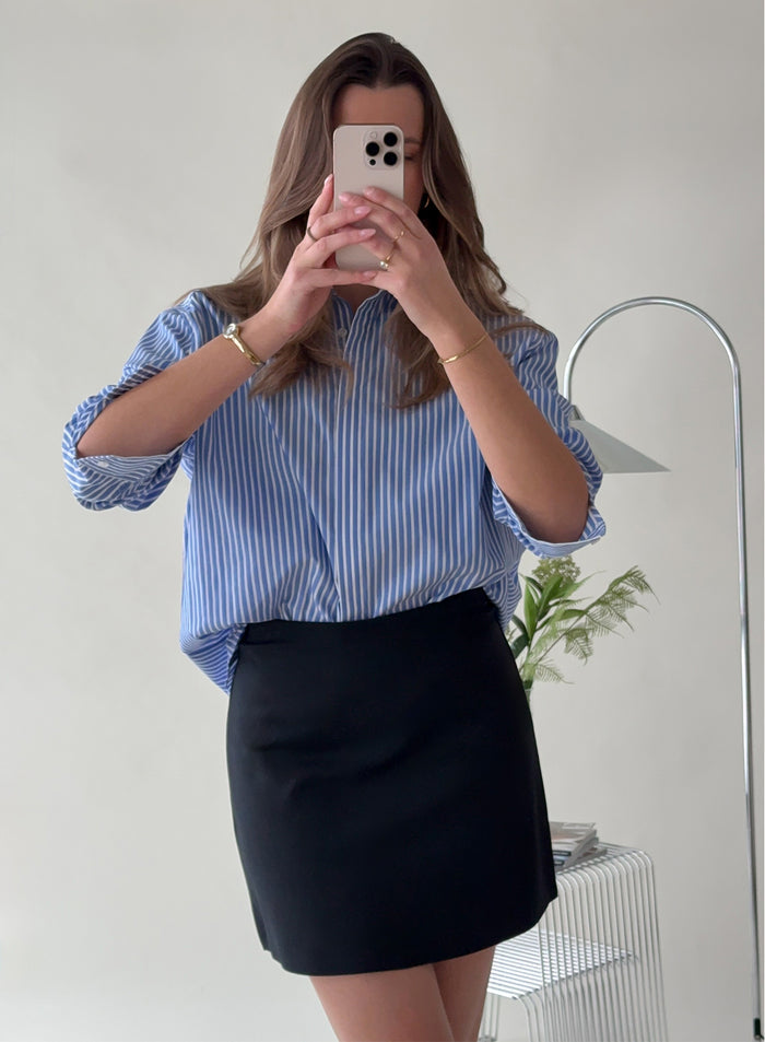 Nainen ottamassa peiliselfietä yllään aim'n Black Luxe Mini Skort. [38-175cm]