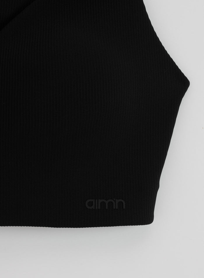 Mustan aim'n Ribbed Performance Support Bra -urheiluliivin yksityiskohta, jossa on ribbikangas ja logo.
