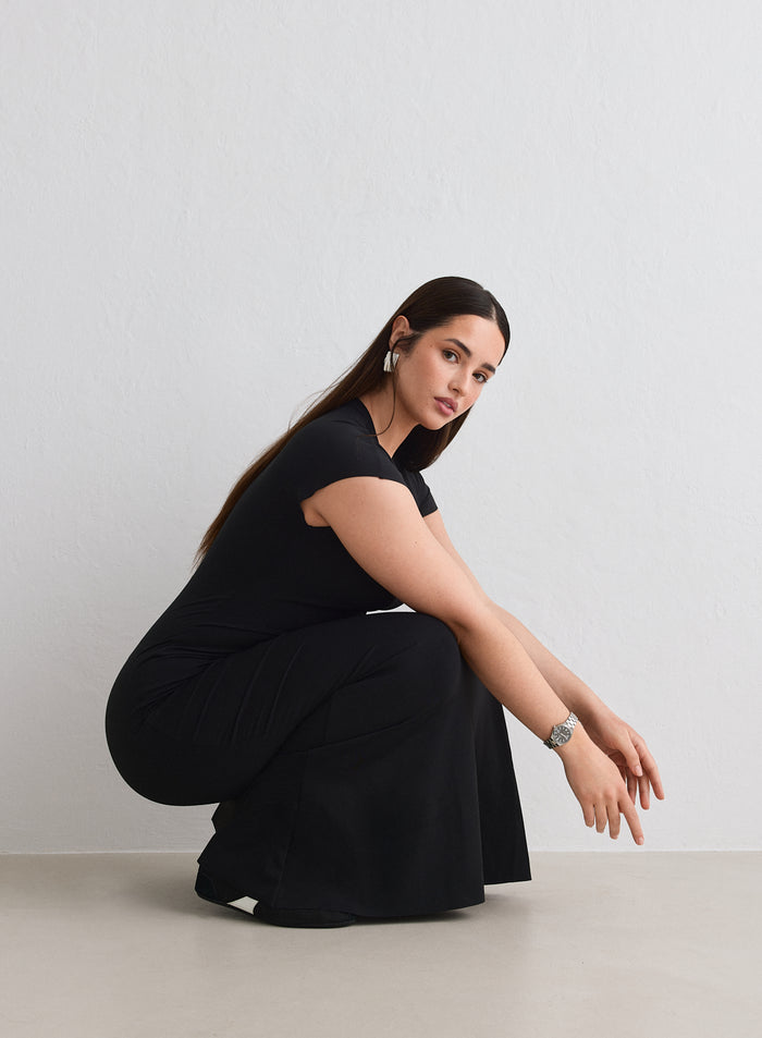 Nainen kyykistyneenä yllään musta aim'n Sense Mermaid Cap Sleeve Dress [L-174cm]