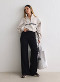 Mallilla päällä Black Sense Pants -housut ja beige poolopaita, kädessään valkoinen kangaskassi [M-170cm]