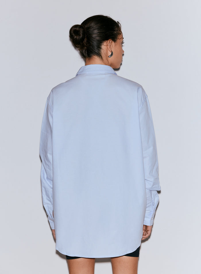 Henkilö takaapäin yllään vaaleansininen ylisuuri Oxford-paita [M-170cm]