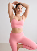 Nainen yllään aim'n blush-värinen Shape Seamless Strap Bra ja yhteensopivat leggingsit poseeraamassa. [L-174cm]