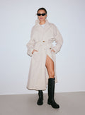 Nainen yllään cafe au lait -värinen Femme Trenchcoat -trenssitakki mustien saappaiden ja aurinkolasien kanssa [M-170CM]