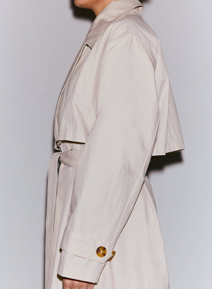 Malli yllään cafe au lait -värinen Femme Trenchcoat, jossa on sidottu vyö ja kilpikonnanvärinen nappiyksityiskohta [M-170cm]