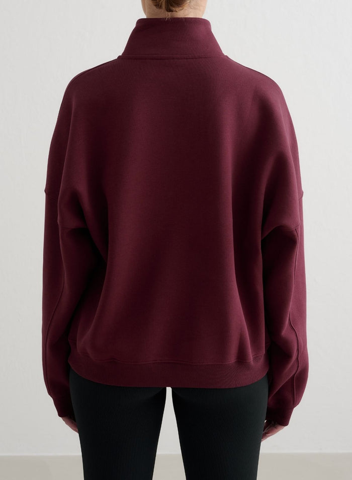 Kirsikanpunainen aim'n Varsity Sweat Half Zip -collegepaita takaa kuvattuna, väljä istuvuus ja pudotetut olkapäät.