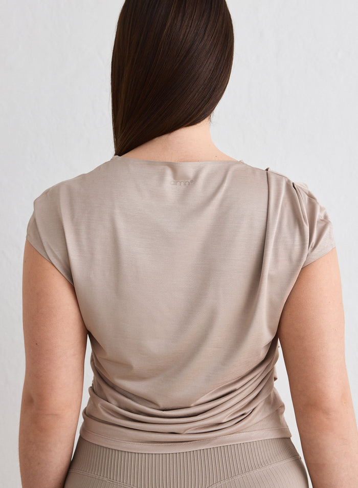 Nainen takaapäin yllään aim'n Dark Clay Luminous Draped Short Sleeve. [L-174cm]