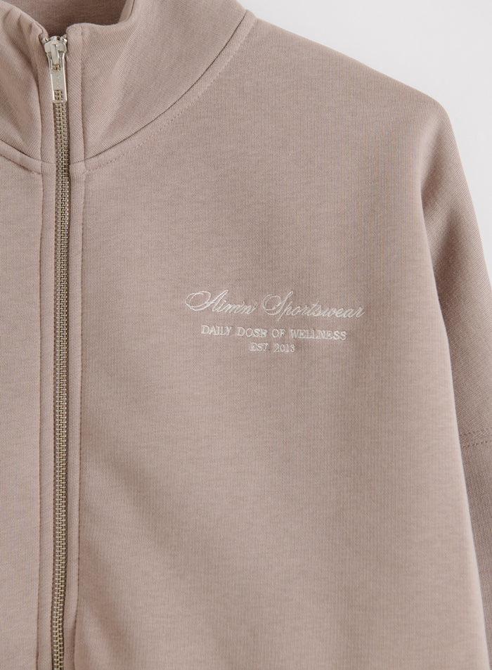 Dark Clay Script Zip Jacket, jossa on korkea kaulus, hopeinen vetoketju ja pehmeä aim'n-kirjailu.