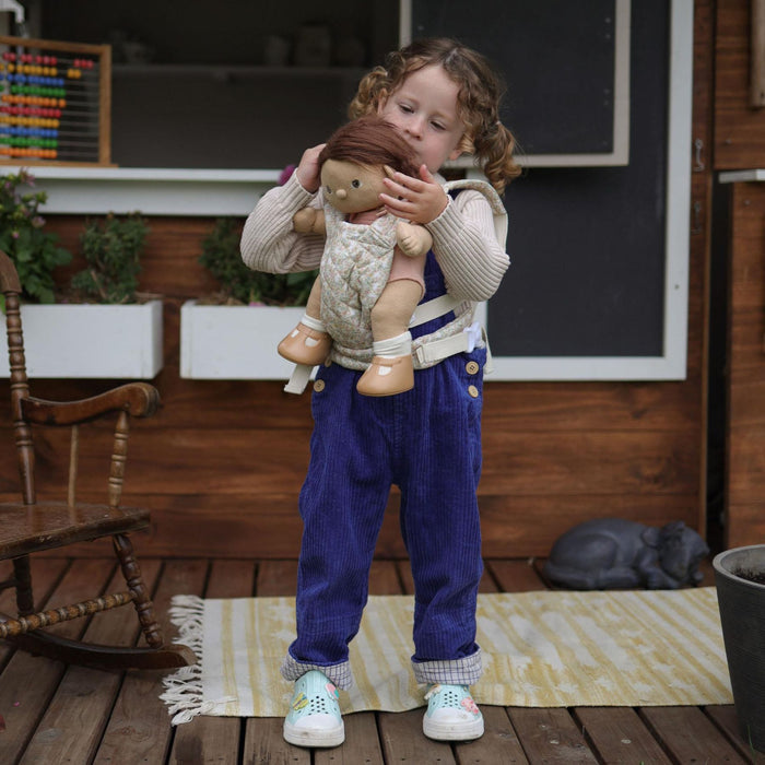 A beige floral-patterned Olli Ella Doll Carrier with padded straps designed for carrying dolls.