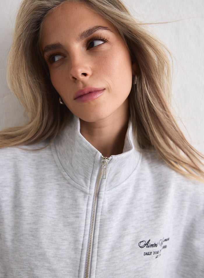 Lähikuva naisesta yllään vaaleanharmaa meleerattu Script Zip Jacket. [M-170cm]