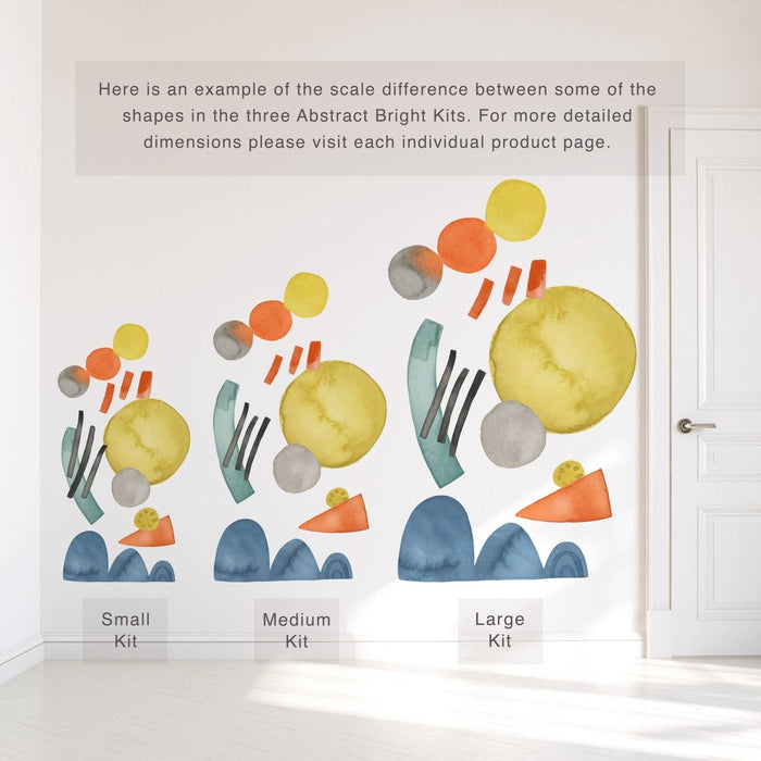 Abstract watercolor wall decals size comparison showing small, medium and large kits on a white wall — colorful yellow circles, orange and gray dots, teal arches and blue hill shapes, peel-and-stick nursery and kids room mural next to white door