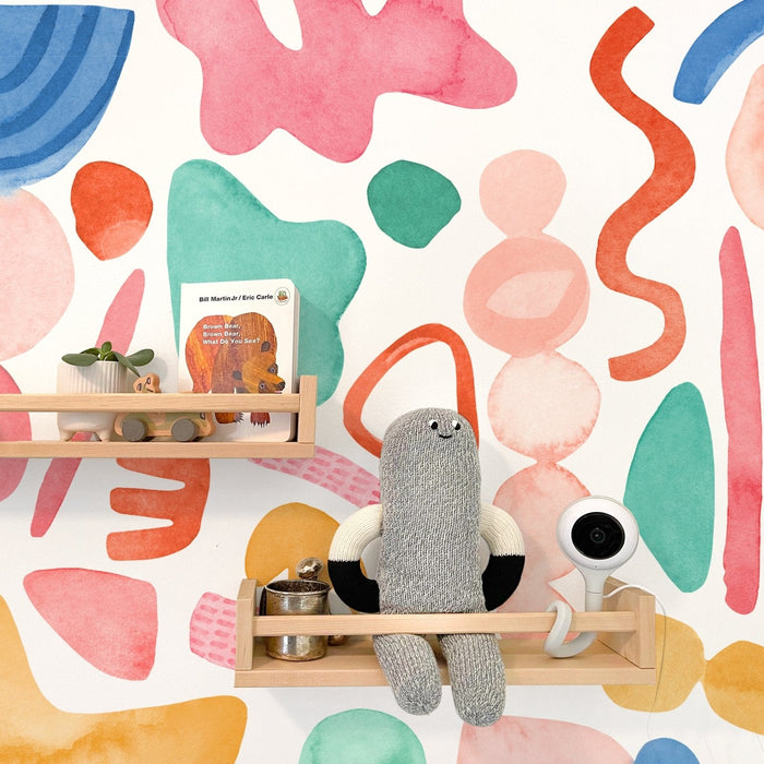 Colorful nursery wall mural with watercolor abstract shapes, wooden floating shelves, stuffed toy, baby monitor and Brown Bear board book