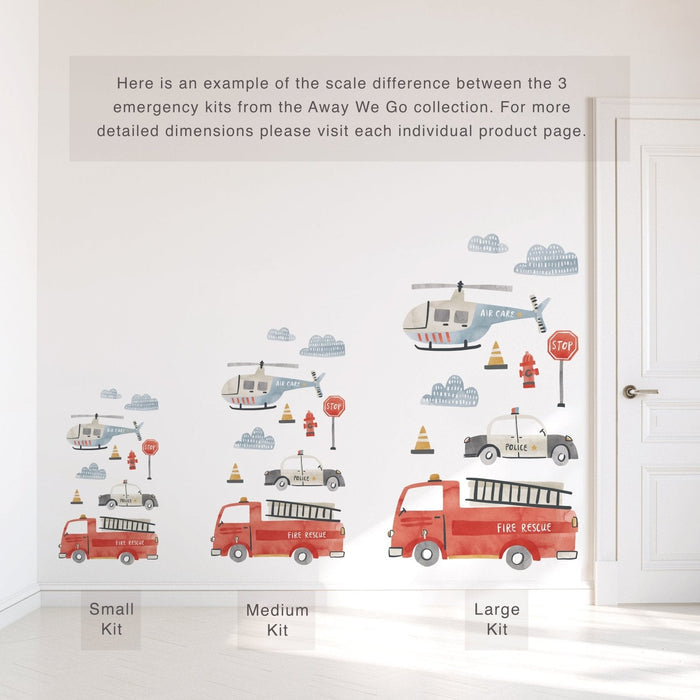 Kids nursery wall decals – Away We Go emergency vehicles featuring red fire rescue trucks, police cars and air care helicopters shown in small, medium and large kit size comparison on a white wall next to a door