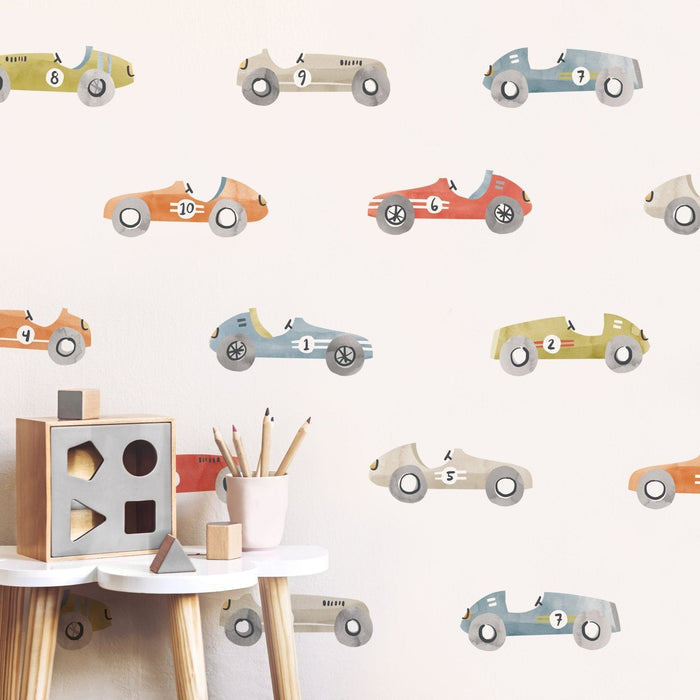 Nursery with pastel vintage race car wall decals, wooden shape sorter toy and pencils on a white stool — kids room decor