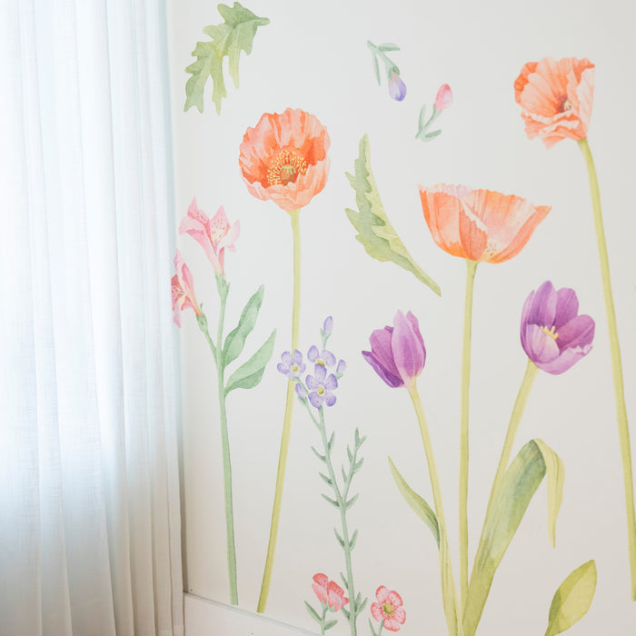 Sheer white curtains beside a watercolor floral wall mural featuring orange poppies, purple tulips and green stems on a pale interior wall