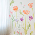 Sheer white curtains beside a watercolor floral wall mural featuring orange poppies, purple tulips and green stems on a pale interior wall