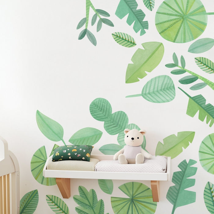 Nursery changing shelf with plush teddy bear, green tropical leaf wall mural and patterned pillow, baby room decor