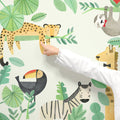 Child pointing at colorful watercolor kids jungle animal wall mural (leopard on branch, toucan, zebra, giraffe, sloth) — nursery and playroom decor wall decal