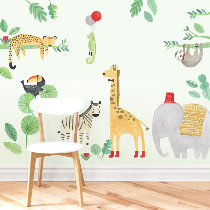 Nursery jungle animal wall mural in watercolor style featuring giraffe, elephant, zebra, leopard, toucan, sloth and chameleon with balloons beside a white wooden chair on a light hardwood floor