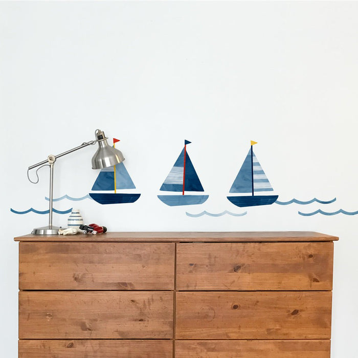 Three blue sailboat wall decals above wooden dresser with silver desk lamp – nautical nursery wall stickers and kids room decor