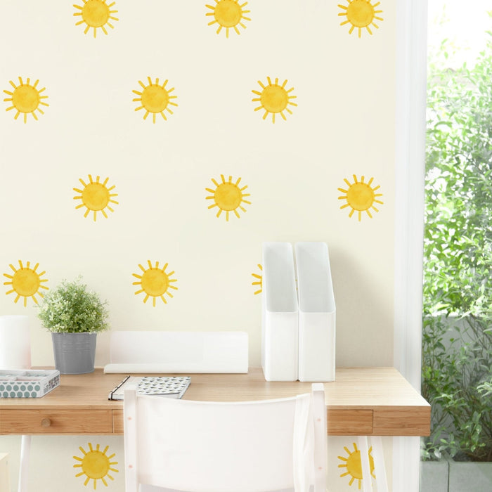Bright desk workspace with yellow sun-pattern wallpaper, white desk organizers, potted plant and natural light