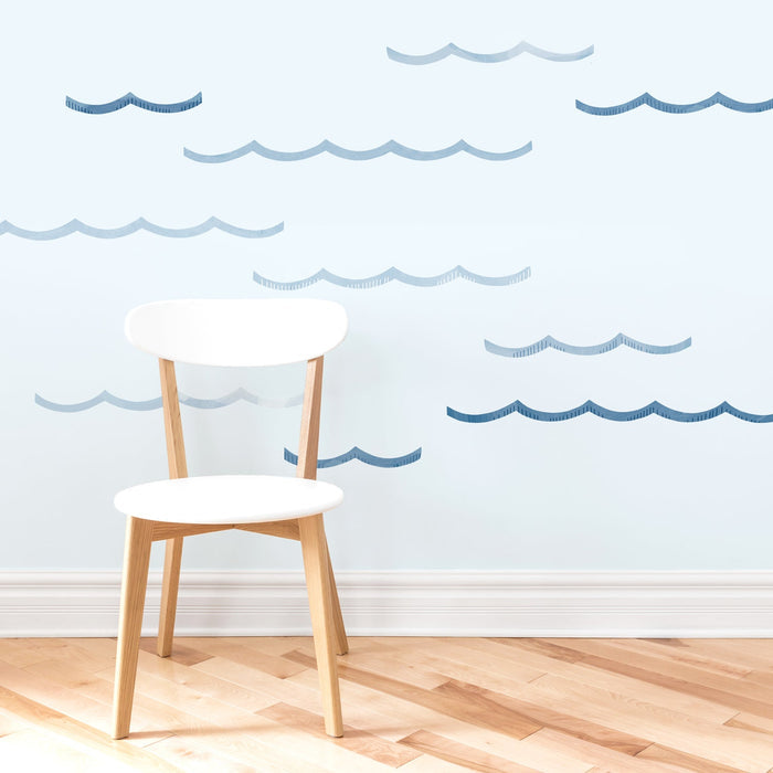 Scandinavian white wooden chair on light hardwood floor against a pale blue wall with blue wave wall decals — coastal nursery decor and modern minimalist interior