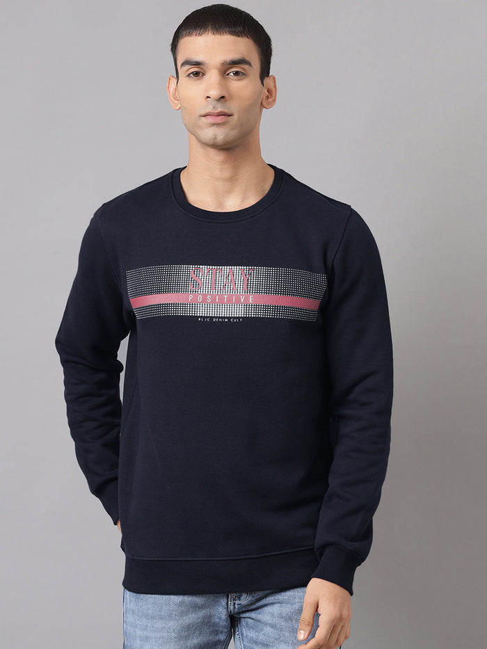 A man wearing a navy blue sweatshirt with 'Stay' text in red and white on the front.