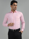 A man wearing a pink textured standard fit formal shirt with full sleeves and a spread collar.