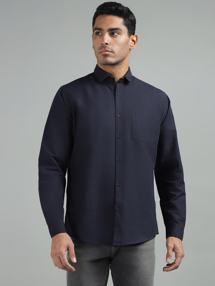 A man wearing a navy-colored, long-sleeved, button-up casual shirt with a spread collar.