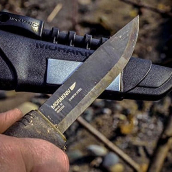Morakniv Bushcraft Survival Black knife held outdoors with sheath, bushcraft gear, custom kit builds A Way Through the Wilderness
