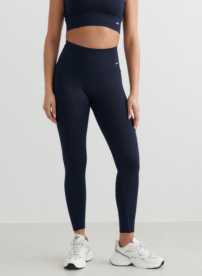 Tummansiniset korkeavyötäröiset aim'n Ribbed Seamless Tights, joissa on second skin -tuntu ja valkoiset tennarit.