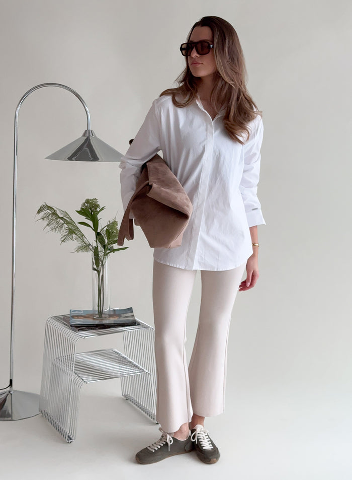Nainen yllään hiekanväriset aim'n Luxe Kick Flare Leggings -leggingsit ja valkoinen paita [38-175cm]