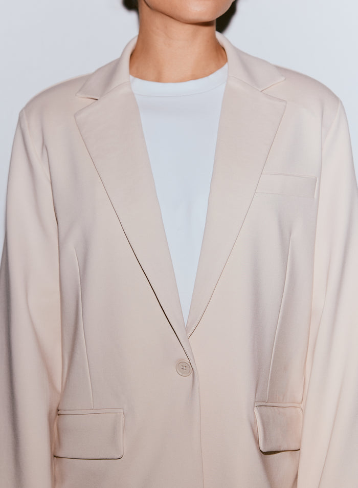 Henkilön lähikuva, jolla on yllään hiekanvärinen Luxe Relaxed Blazer valkoisen t-paidan päällä [40-170CM]
