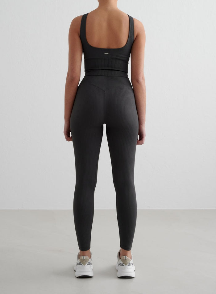 Tummanharmaat aim'n Ribbed Seamless Tall Tights ja yhteensopiva crop-toppi takaapäin kuvattuna.