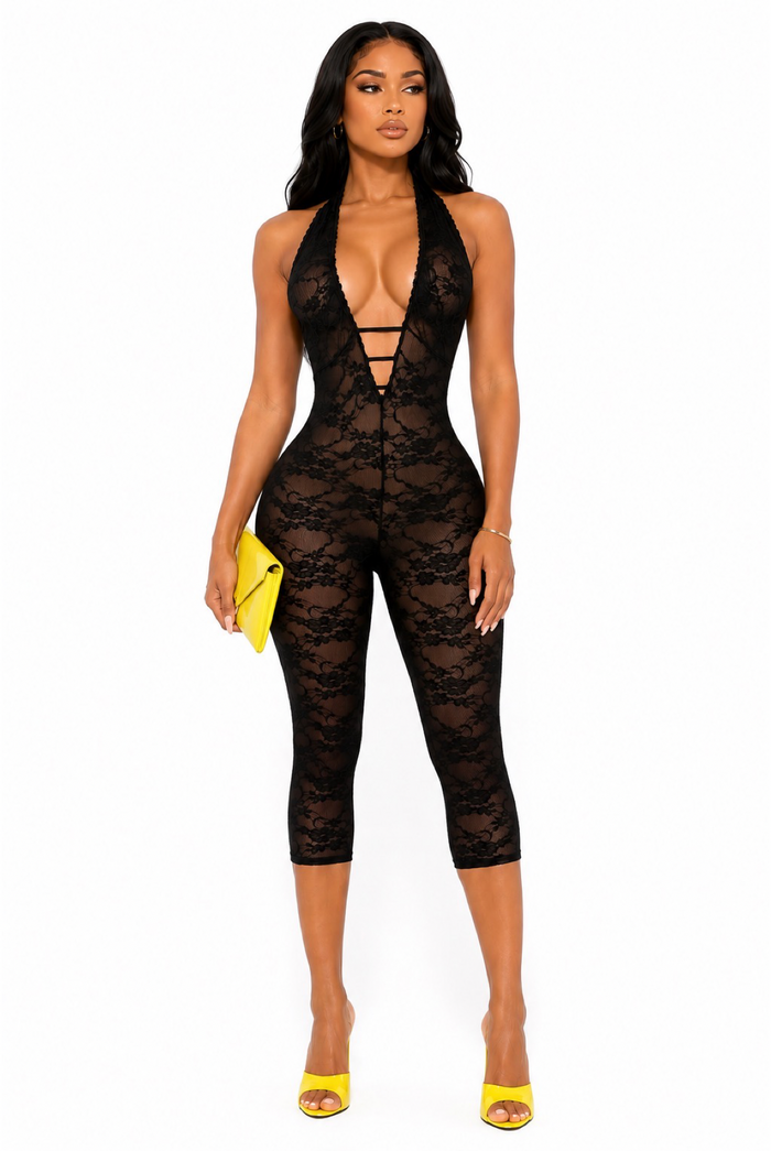 Angled front pose of black lace halter capri romper with deep V front, capri length, neon yellow heels, and matching clutch.