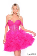 A woman wears a strapless, ruffled neon pink tulle dress with an embellished corset bodice.