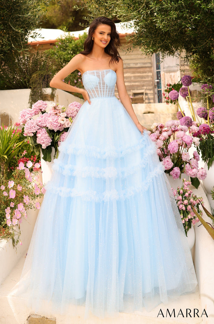 A woman in a blue tulle ball gown poses among pink and purple flowers in a garden setting.