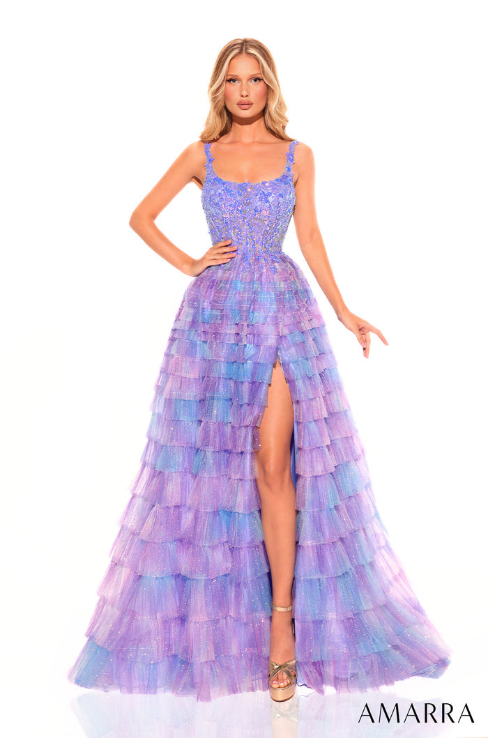 A tall model wears a tiered, shimmering Electric Blue ball gown with a thigh-high slit and fitted bodice.