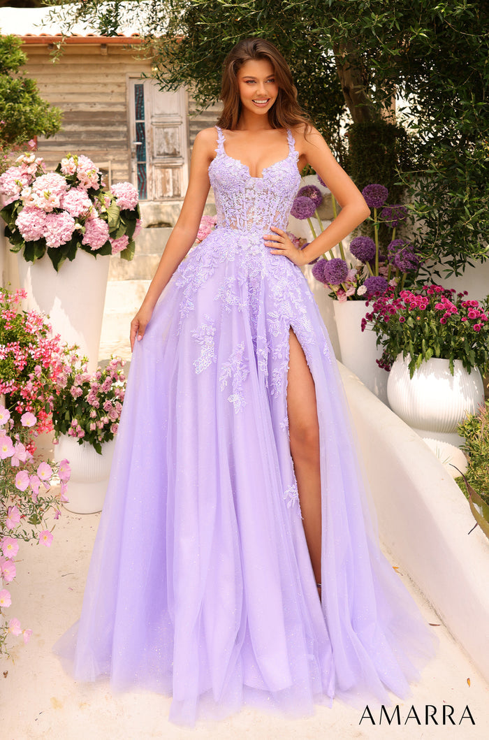 A woman wears a flowing lilac ballgown with lace details and a high slit, standing in a garden with pink and purple flowers.