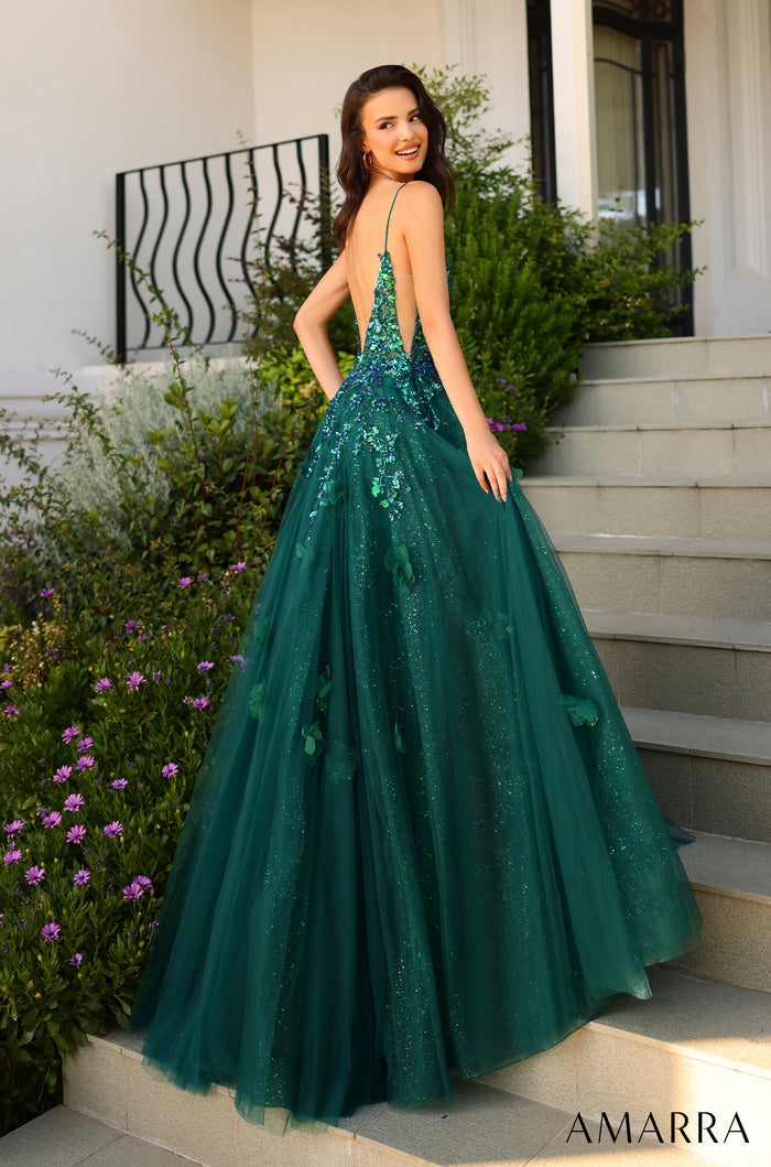 A shimmering emerald green ball gown with sequined bodice and full tulle skirt, worn on stone steps near purple flowers.
