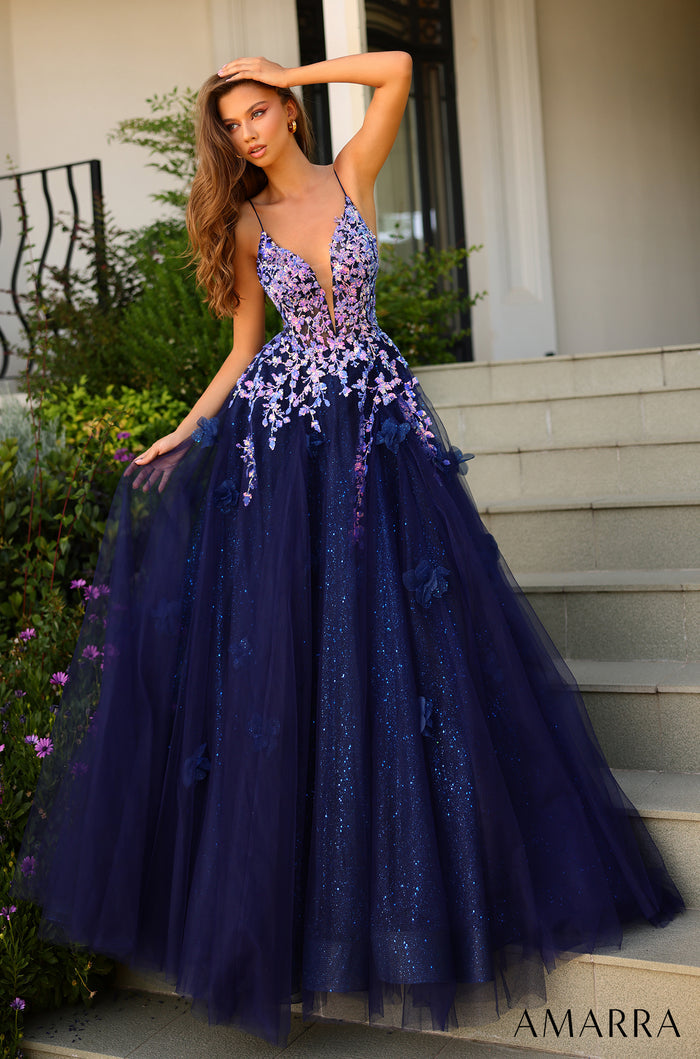 A model wears a navy ball gown with lilac floral appliqués and a plunging neckline, standing on stone steps.