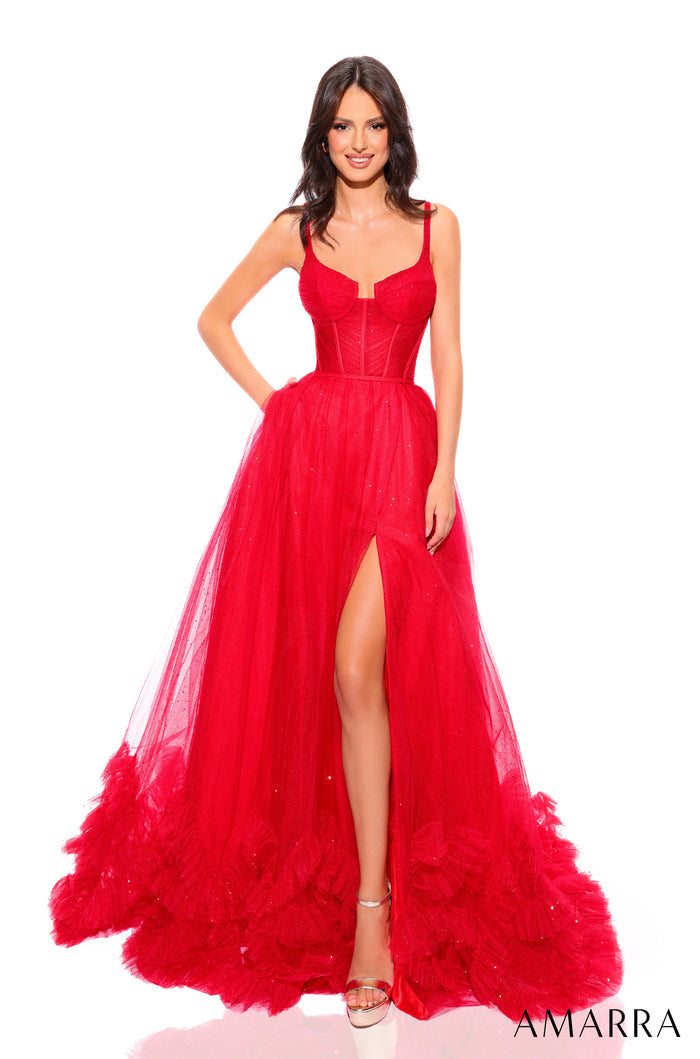 A woman wears a dramatic red tulle gown with a thigh-high slit and corseted bodice, posing against a white background.